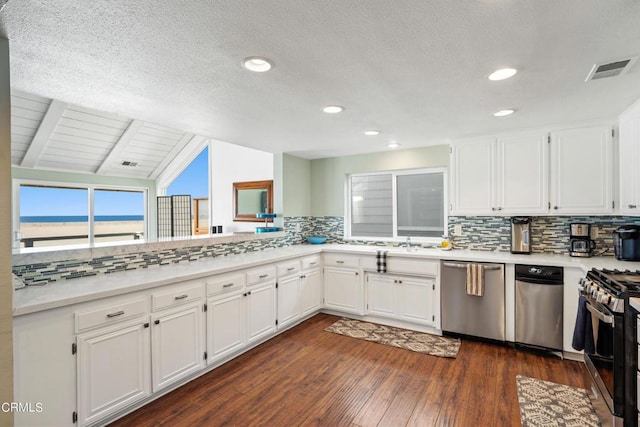 3371 Ocean Dr, Oxnard, CA 93035 - kitchen featuring lofted ceiling with beams, light countertops, stainless steel appliances, white cabinetry, and dark wood-style floors