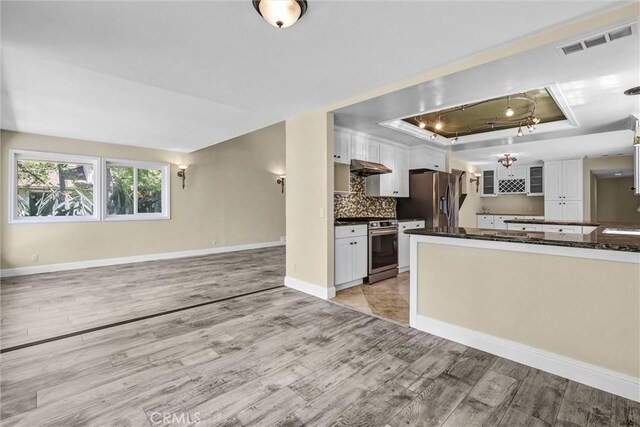 22839 Ridge Route Ln, Lake Forest, CA 92630 - kitchen with a tray ceiling, light wood-type flooring, visible vents, white cabinetry, and appliances with stainless steel finishes