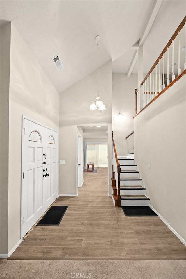 entryway featuring baseboards, an inviting chandelier, stairway, visible vents, and high vaulted ceiling