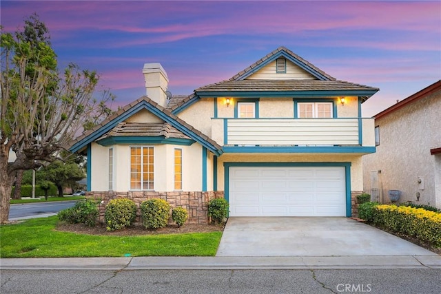 traditional-style house with stucco siding, a chimney, driveway, stone siding, and a garage