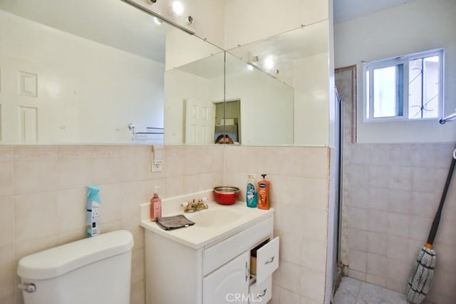 bathroom with tile walls, toilet, a shower with door, and vanity