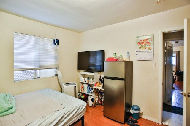 bedroom with freestanding refrigerator, wood finished floors, and baseboards
