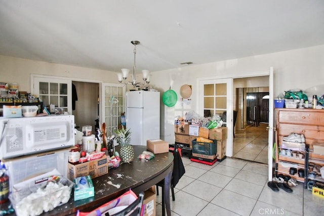 dining area with a chandelier, light tile patterned flooring, and french doors