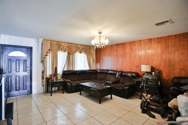 living area featuring a chandelier, light tile patterned floors, and wooden walls