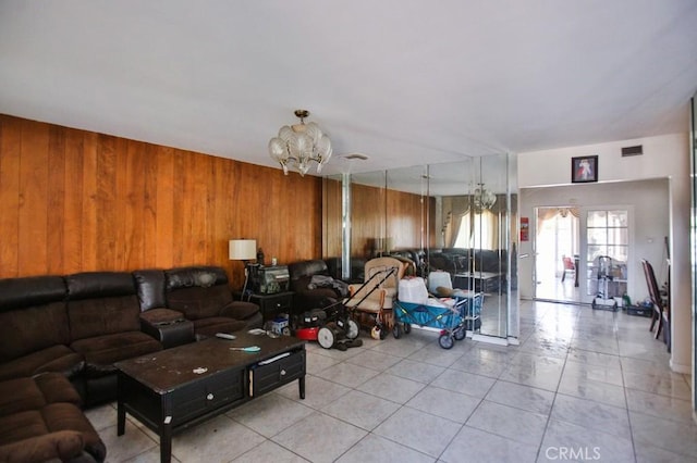 living room featuring wood walls, a chandelier, and light tile patterned floors