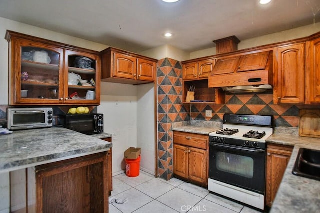 kitchen featuring range with gas stovetop, custom range hood, black microwave, light tile patterned flooring, and decorative backsplash