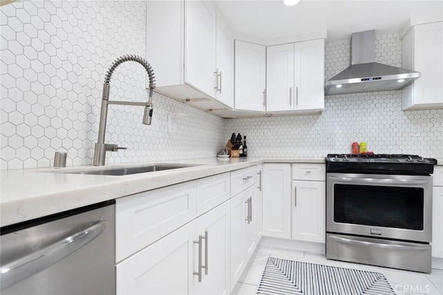 kitchen with light countertops, appliances with stainless steel finishes, a sink, wall chimney range hood, and backsplash