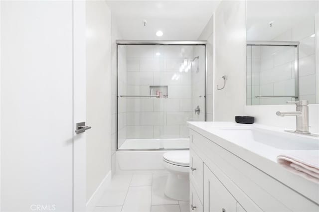 bathroom featuring toilet, tile patterned floors, vanity, and enclosed tub / shower combo