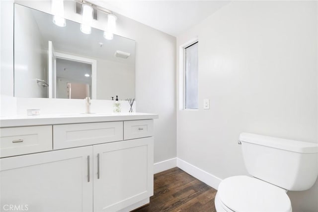 bathroom with toilet, vanity, baseboards, and wood finished floors
