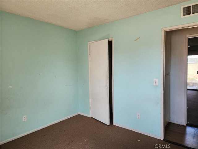 unfurnished bedroom featuring a closet, carpet floors, a textured ceiling, baseboards, and visible vents