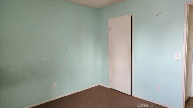 unfurnished bedroom with baseboards, a closet, and dark colored carpet