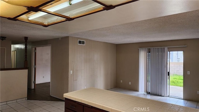 unfurnished room featuring visible vents, light tile patterned floors, and a textured ceiling