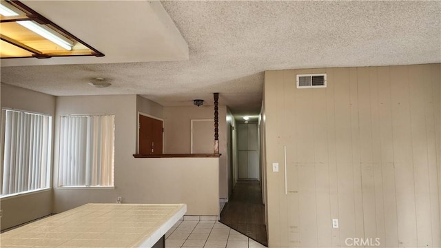interior space featuring tile countertops, visible vents, a textured ceiling, and light tile patterned floors