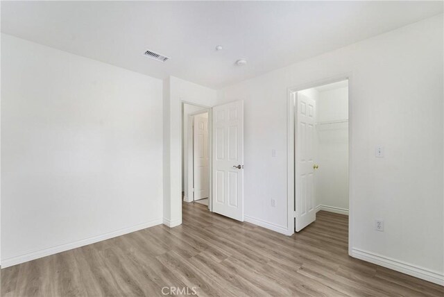 1510 Timberwood, Irvine, CA 92620 - unfurnished bedroom featuring light wood finished floors, a walk in closet, and baseboards