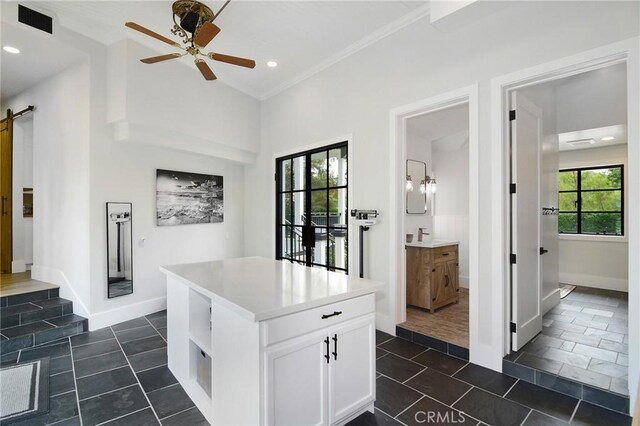 kitchen featuring light countertops, ceiling fan, a barn door, white cabinetry, and open shelves