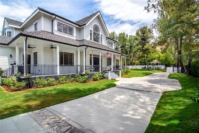 view of front of home with a front lawn, covered porch, fence, and a ceiling fan