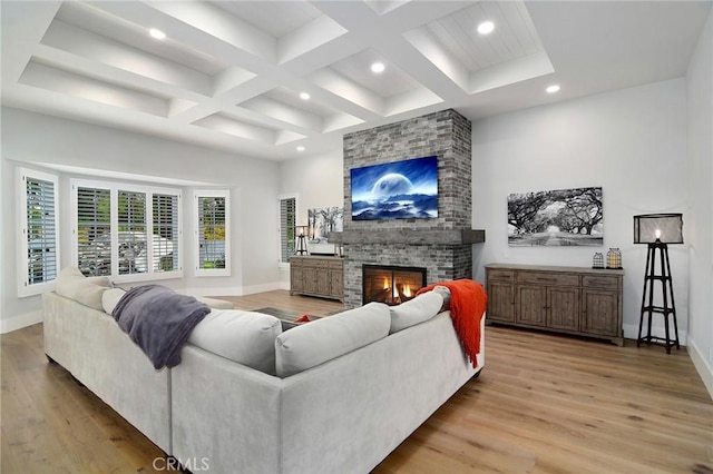 living room featuring a fireplace, coffered ceiling, baseboards, and light wood finished floors