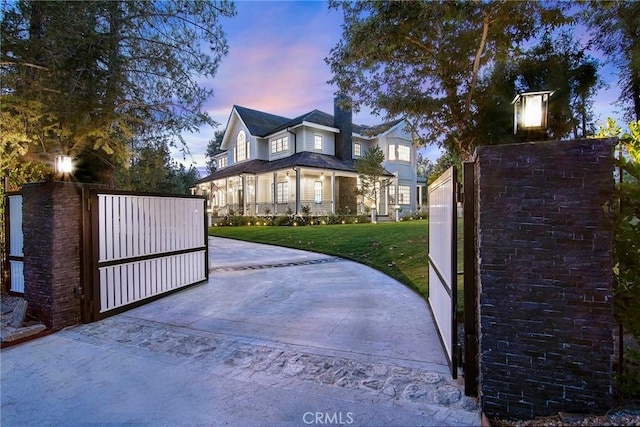 gate at dusk featuring a lawn
