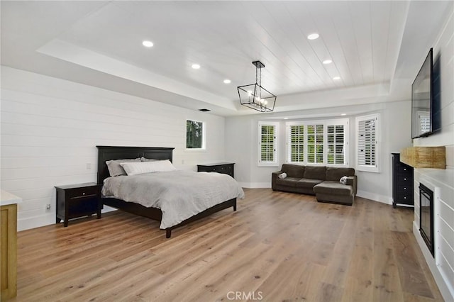 bedroom featuring baseboards, recessed lighting, light wood-type flooring, and a raised ceiling