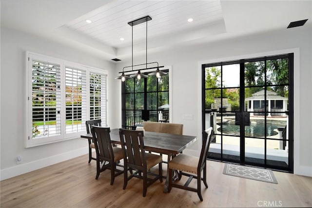dining area with a raised ceiling, recessed lighting, baseboards, and wood finished floors