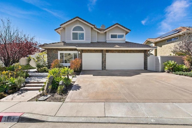traditional home featuring driveway, a garage, stone siding, and a tile roof