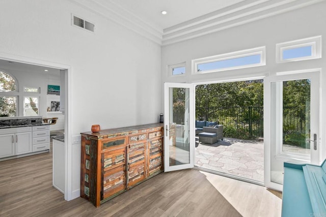 doorway with a towering ceiling, visible vents, french doors, and wood finished floors
