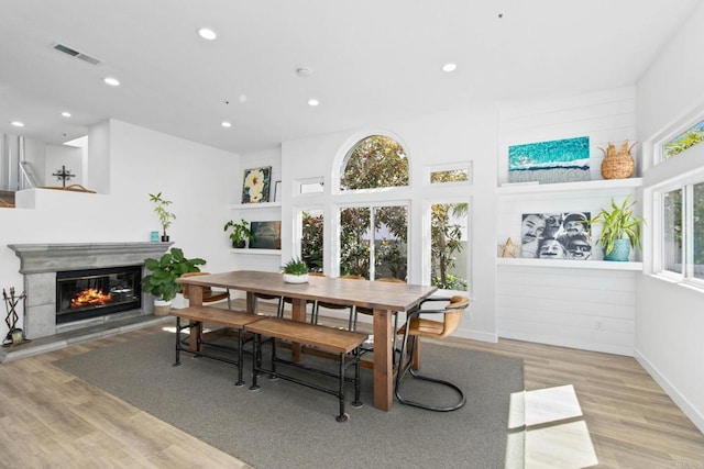 dining space with visible vents, recessed lighting, a glass covered fireplace, and wood finished floors