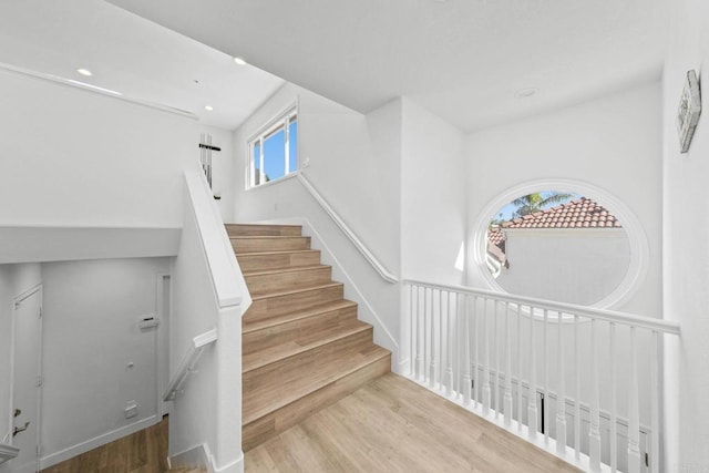 stairs with wood finished floors and recessed lighting
