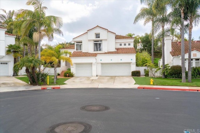 4981 Marin Dr, Oceanside, CA 92056 - mediterranean / spanish-style home featuring a garage, fence, stucco siding, a tiled roof, and driveway
