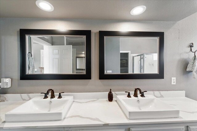 4981 Marin Dr, Oceanside, CA 92056 - full bathroom with double vanity, a textured wall, a shower stall, and a sink