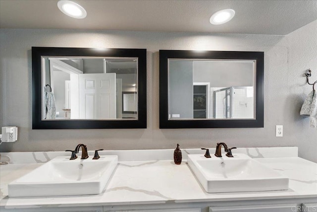 4981 Marin Dr, Oceanside, CA 92056 - bathroom with double vanity, a textured wall, and an enclosed shower