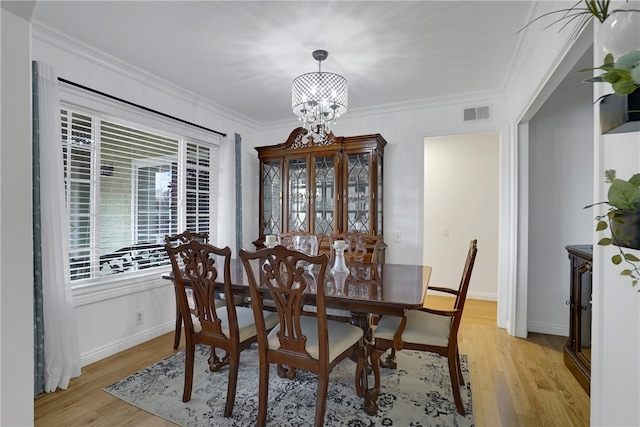 dining area featuring light wood-style flooring, a notable chandelier, and crown molding