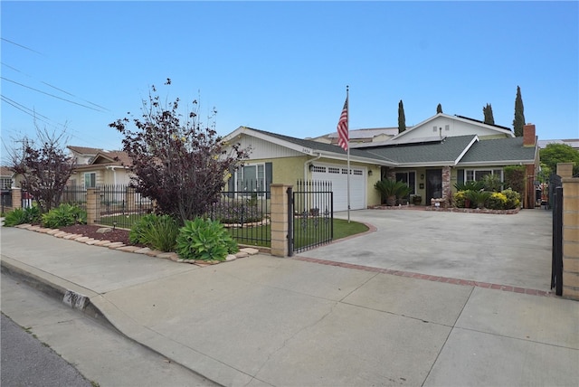 single story home featuring roof mounted solar panels, a fenced front yard, a garage, and concrete driveway