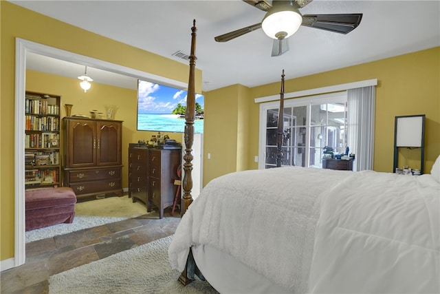 bedroom featuring multiple windows, visible vents, stone tile flooring, and access to outside
