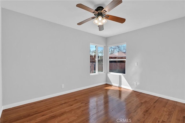 unfurnished room featuring wood finished floors, baseboards, and a ceiling fan