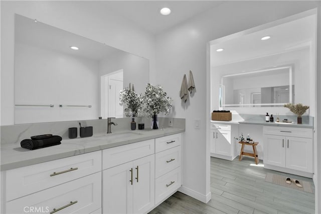 bathroom featuring baseboards, recessed lighting, vanity, and wood finished floors