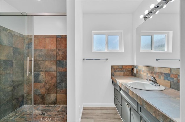 full bath with a shower stall, vanity, wood finished floors, and decorative backsplash