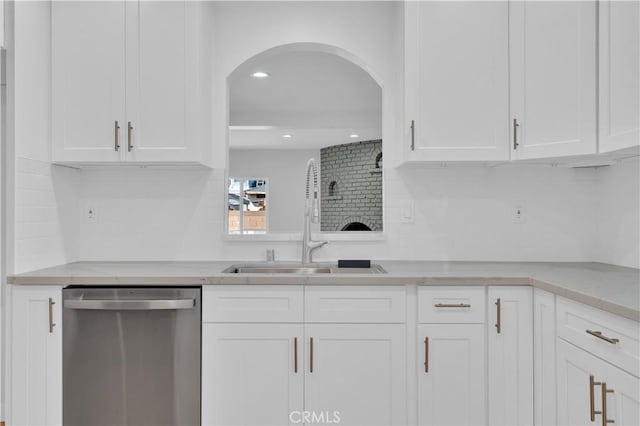 kitchen with tasteful backsplash, stainless steel dishwasher, arched walkways, and white cabinets