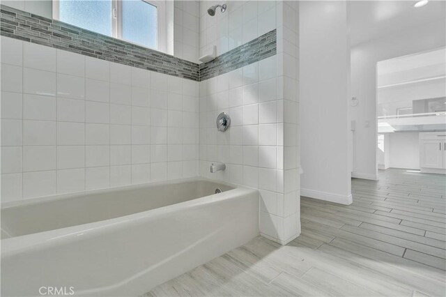 full bath with baseboards, wood finish floors, shower / bath combination, and vanity