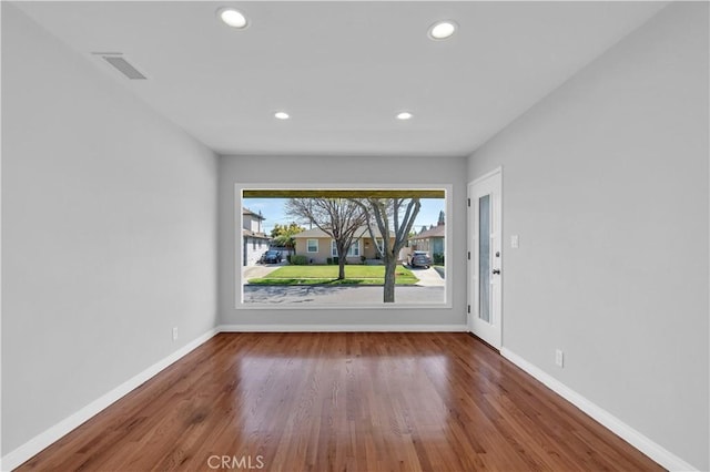 empty room featuring wood finished floors, baseboards, visible vents, and recessed lighting