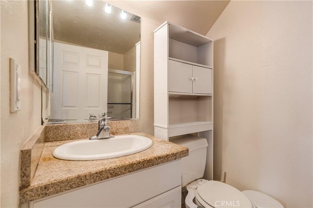 full bath featuring toilet, a shower with shower door, and vanity