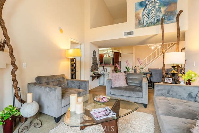living area with a high ceiling, stairs, and visible vents