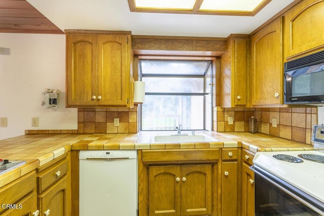 kitchen featuring white appliances, backsplash, a sink, and brown cabinetry