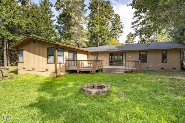 rear view of property featuring an outdoor fire pit, a yard, crawl space, and a deck