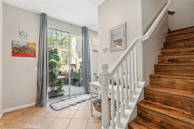 entrance foyer featuring light tile patterned floors, baseboards, and stairs
