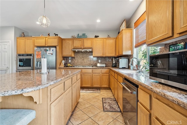 kitchen featuring appliances with stainless steel finishes, under cabinet range hood, light stone countertops, decorative backsplash, and a sink