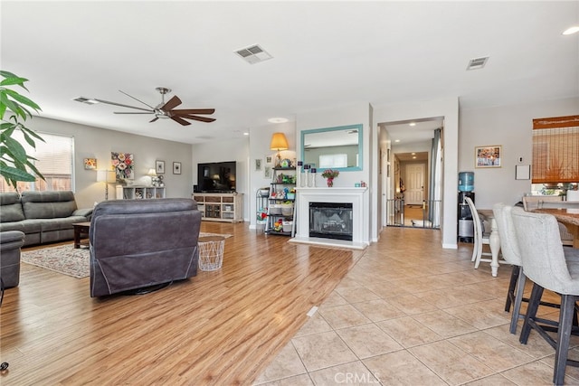 living area featuring light tile patterned floors, visible vents, and a ceiling fan