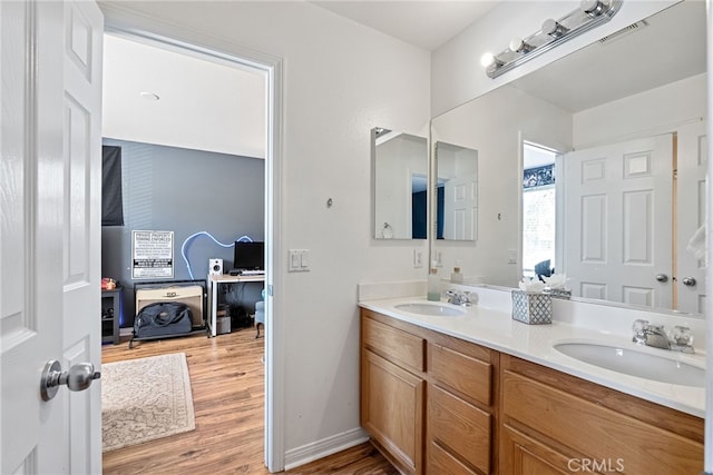 full bath with double vanity, visible vents, a sink, and wood finished floors