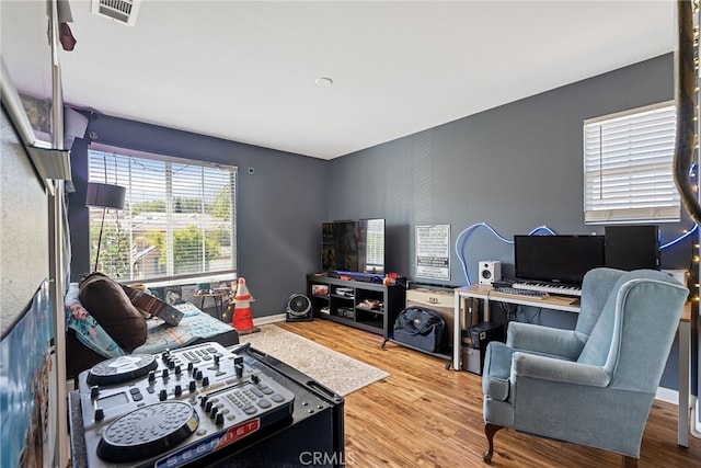 living area with wood finished floors, baseboards, and visible vents