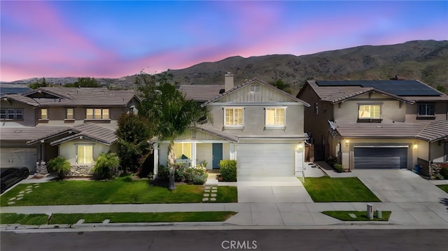 traditional-style home featuring a mountain view, solar panels, a yard, a garage, and driveway